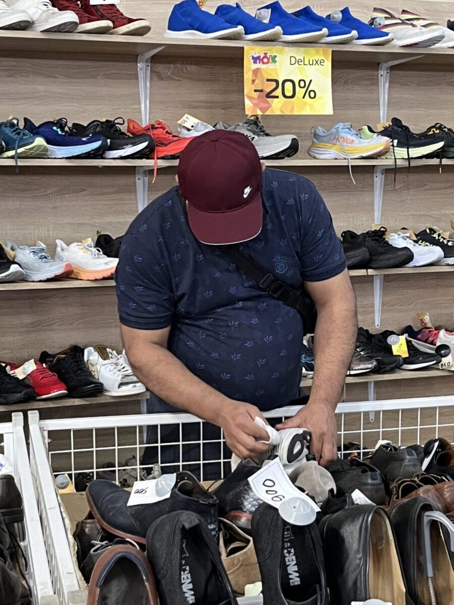 працівник секонду чистить взуття на продаж