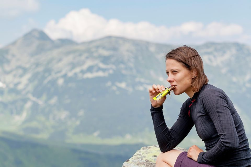 дівчина в горах їсть батончик