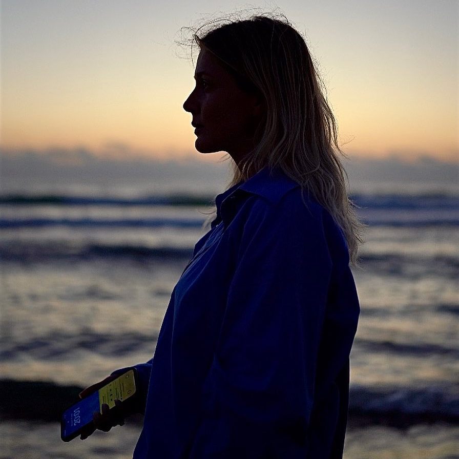 Співачка Kola, Анастасія Прудіус, дівчина з телефоном блія моря, захід сонця на морі, захід сонця на березі