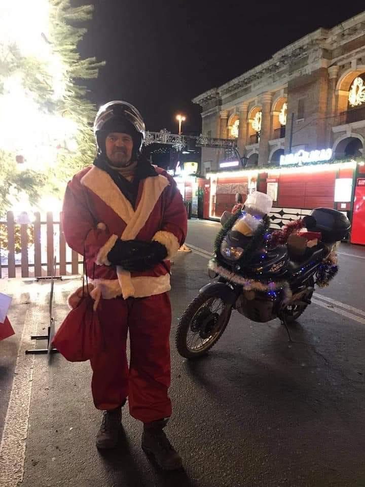 Волонтер у костюмі Санти стоїть біля мотоциклу