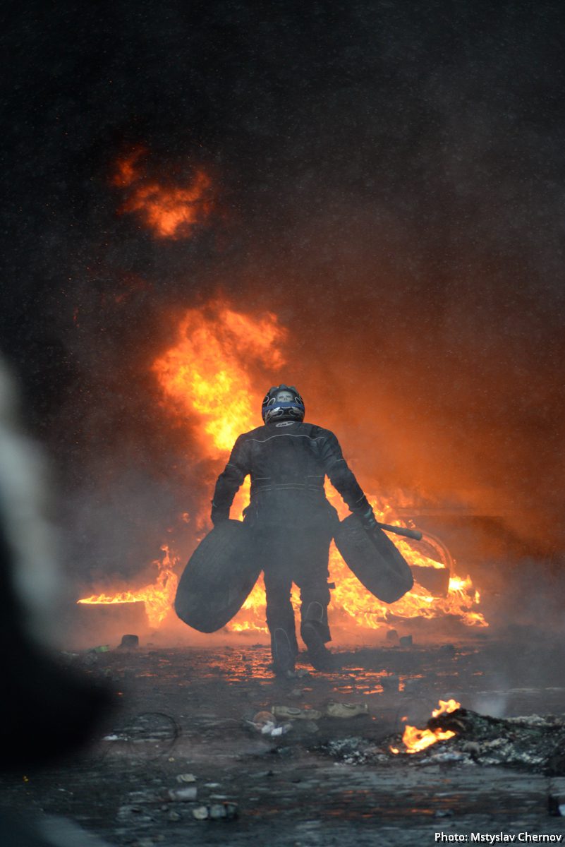 Героїв Небесної Сотні-Protester bringing tires to the fire set by the protesters to prevent internal forces from crossing the barricade line. Kyiv, Ukraine. Jan 22, 2014.-37083