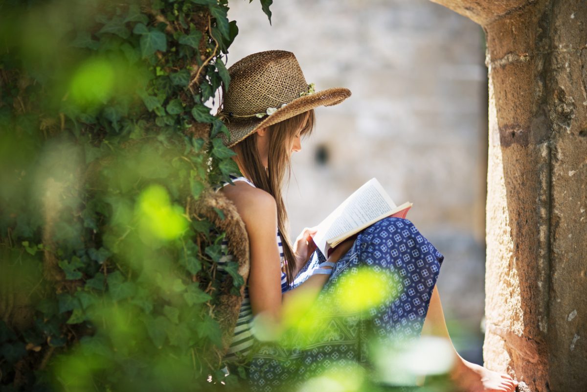 книга на літо-Teenage girl reading a book in an old ruined garden. The girl is sitting in a ruined vine covered window,-66213